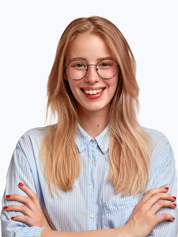 A person with long blonde hair, wearing glasses and a light blue striped shirt, stands with their arms crossed and smiles at the camera.