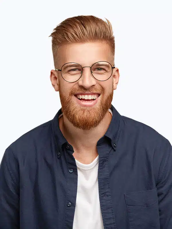 A man with short, styled light brown hair, wearing round glasses, a white shirt, and a blue button-up shirt, smiles at the camera against a plain white background.